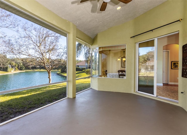 unfurnished sunroom with ceiling fan and a water view