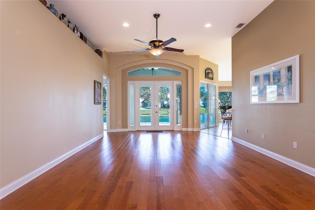 unfurnished living room featuring ceiling fan, a high ceiling, light hardwood / wood-style flooring, and french doors