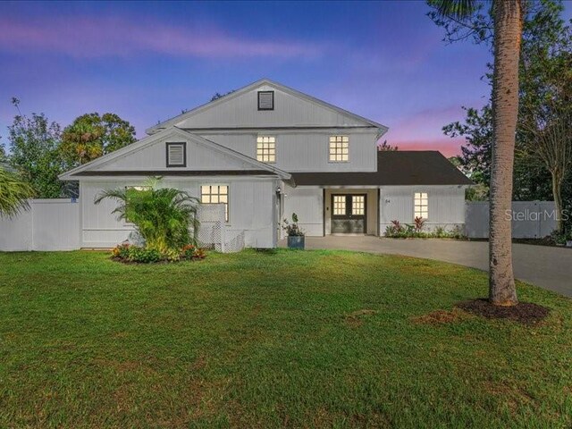 back house at dusk featuring a lawn and french doors