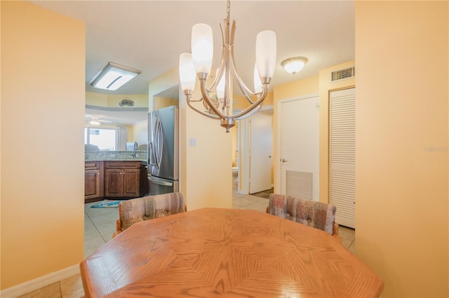 tiled dining room with ceiling fan with notable chandelier