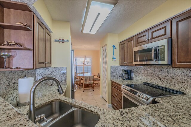 kitchen featuring light stone countertops, appliances with stainless steel finishes, tasteful backsplash, and sink