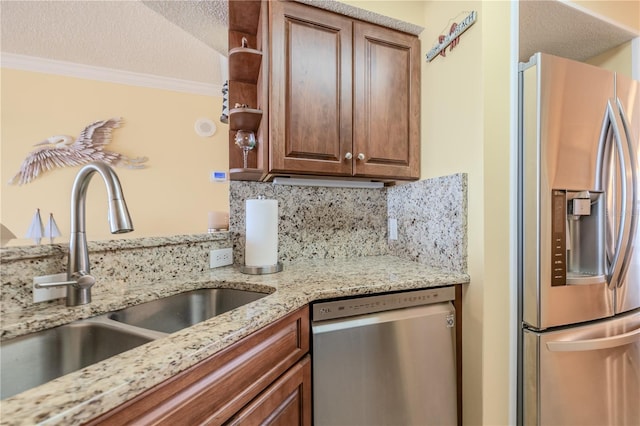 kitchen with light stone countertops, appliances with stainless steel finishes, ornamental molding, and sink