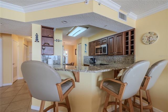 1183 Ocean Shore Blvd Unit 6040, Ormond Beach, FL 32176 - kitchen featuring open shelves, stainless steel microwave, a textured ceiling, tasteful backsplash, and a breakfast bar