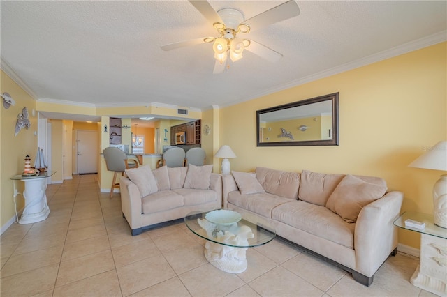 living room with ceiling fan, light tile patterned floors, a textured ceiling, and ornamental molding