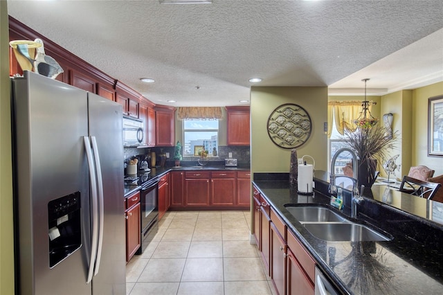 kitchen with sink, stainless steel appliances, tasteful backsplash, decorative light fixtures, and light tile patterned floors