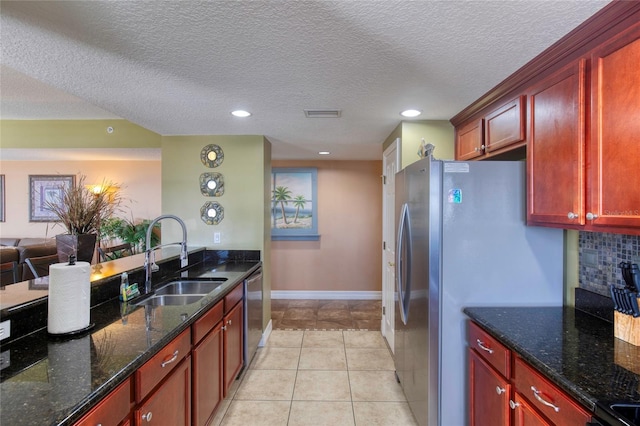 kitchen featuring a textured ceiling, sink, dark stone counters, and stainless steel appliances