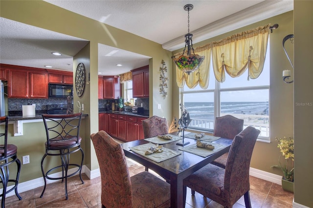 tiled dining space featuring a textured ceiling, a water view, and sink