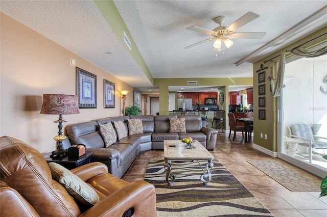 living room featuring tile patterned floors, ceiling fan, and a textured ceiling