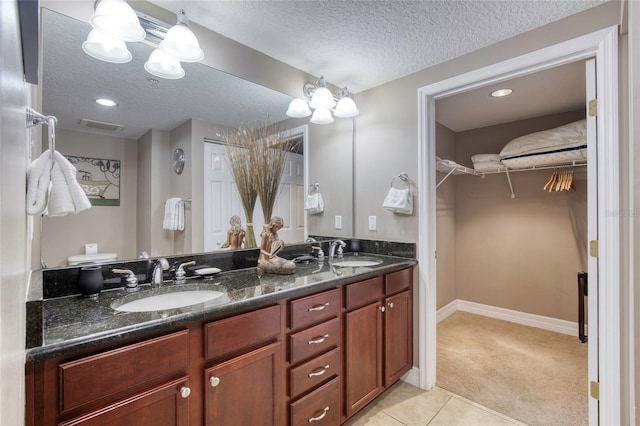 bathroom with tile patterned floors, vanity, and a textured ceiling