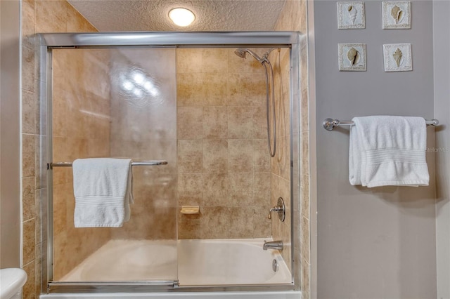 bathroom with toilet, shower / bath combination with glass door, and a textured ceiling