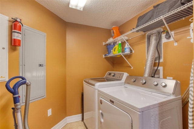 laundry room featuring a textured ceiling, electric panel, and washing machine and clothes dryer