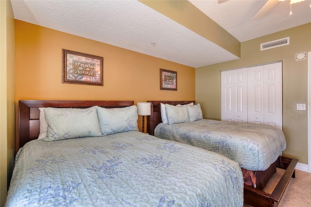 bedroom with carpet flooring, ceiling fan, a closet, and a textured ceiling