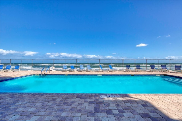 view of pool with a water view and a patio