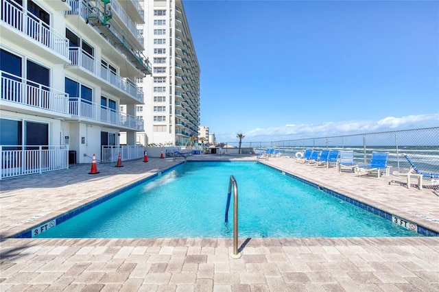 view of swimming pool featuring a water view and a patio