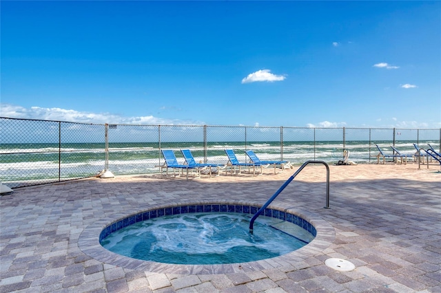 view of pool with a community hot tub, a patio, and a water view