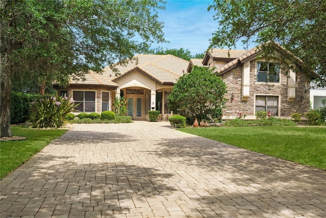 view of front of house featuring stone siding, a tile roof, and a front lawn