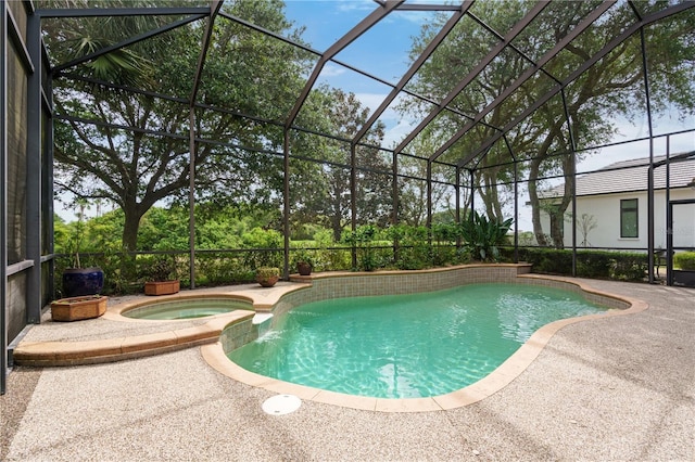 view of swimming pool featuring a pool with connected hot tub, a patio area, and a lanai