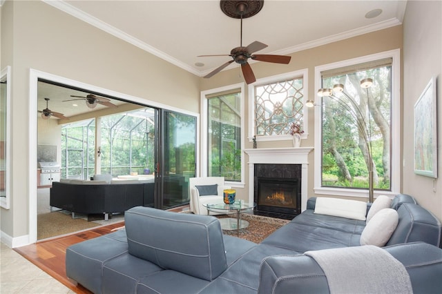 living area featuring ornamental molding, a sunroom, a tiled fireplace, and wood finished floors