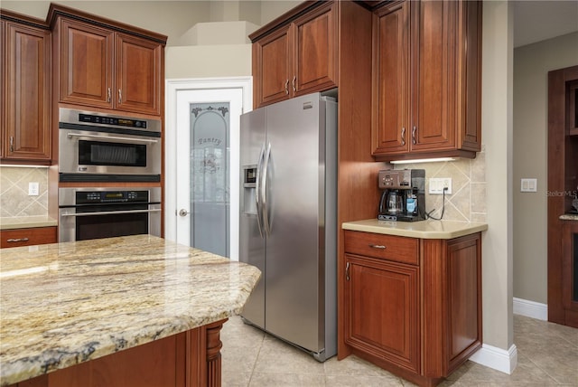 kitchen featuring appliances with stainless steel finishes, light tile patterned flooring, backsplash, and baseboards