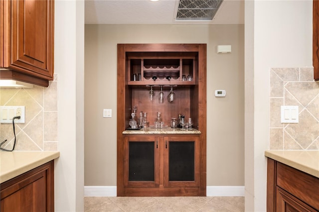 bar featuring baseboards, tile patterned flooring, visible vents, and decorative backsplash