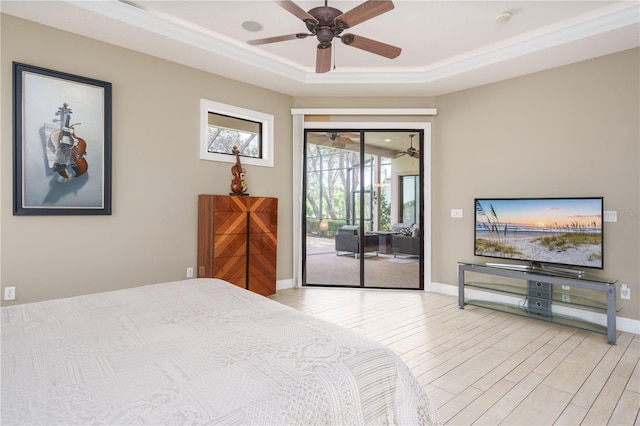 bedroom featuring baseboards, light wood finished floors, a raised ceiling, and access to exterior