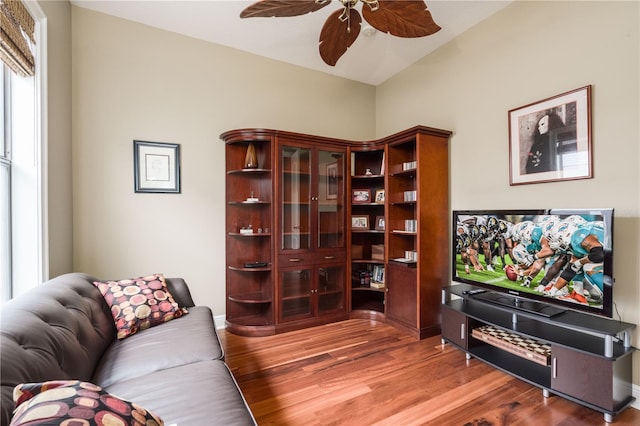 living room with ceiling fan, baseboards, and wood finished floors