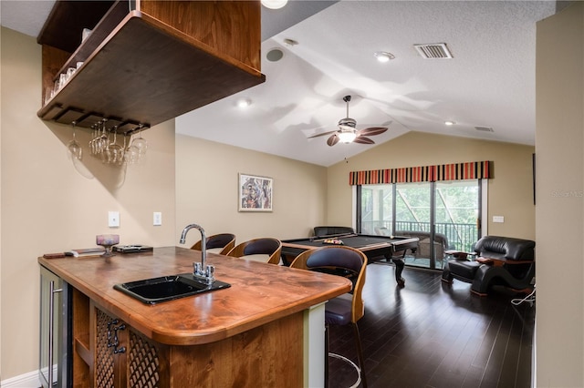 kitchen with lofted ceiling, visible vents, a sink, wood finished floors, and butcher block countertops