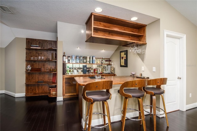 bar with lofted ceiling, dark wood-style floors, wet bar, and visible vents