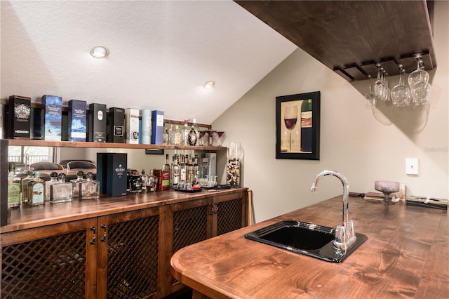 bar featuring a dry bar, vaulted ceiling, and a sink