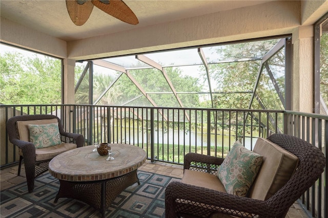 sunroom featuring ceiling fan and a water view