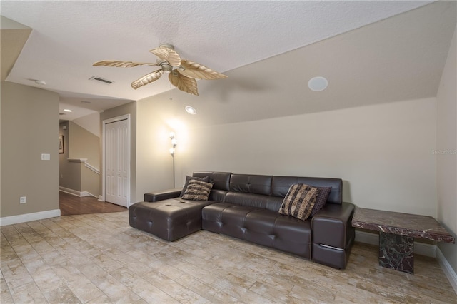 living area with ceiling fan, a textured ceiling, visible vents, and baseboards