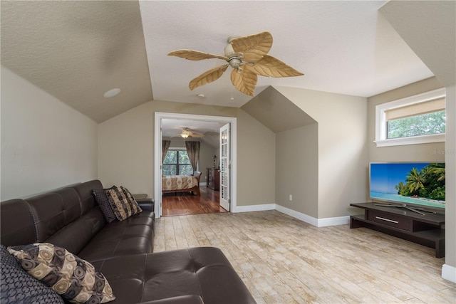 living area with baseboards, lofted ceiling, ceiling fan, a textured ceiling, and light wood-style floors