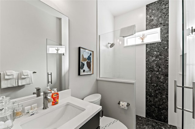 bathroom with vanity, toilet, and a tile shower