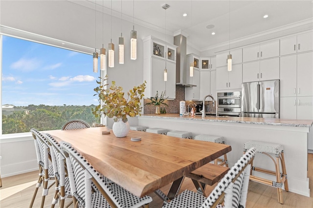 dining area featuring light wood-type flooring, ornamental molding, and sink