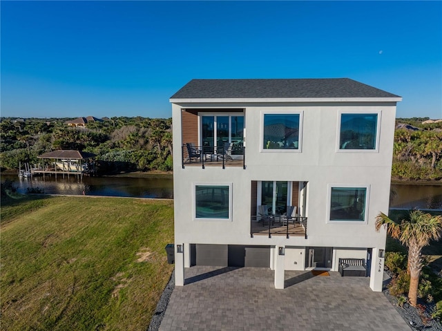 back of property featuring a water view, a garage, and a lawn