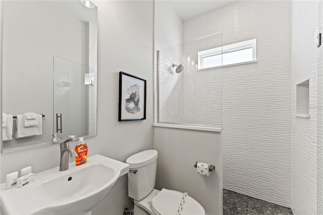 bathroom featuring a tile shower, toilet, and sink