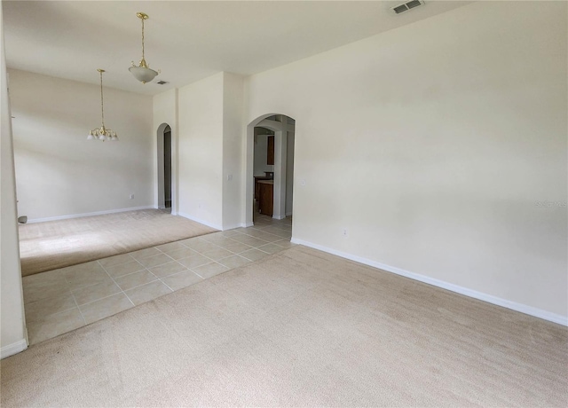 spare room featuring a chandelier and light colored carpet