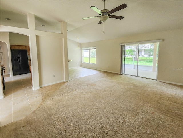 spare room featuring ceiling fan, light tile patterned floors, and vaulted ceiling