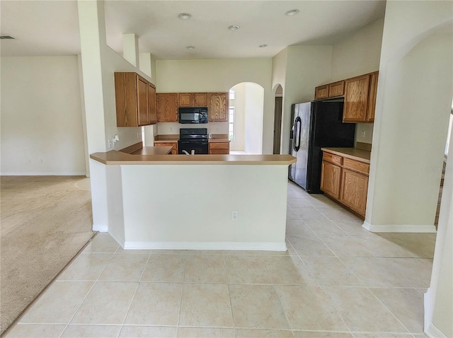 kitchen featuring black appliances, light colored carpet, and kitchen peninsula