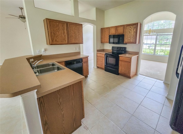 kitchen with ceiling fan, sink, kitchen peninsula, light tile patterned floors, and black appliances