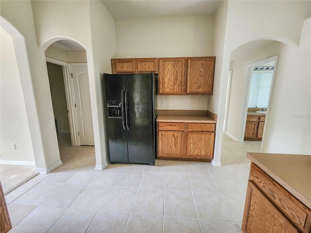 kitchen with black refrigerator with ice dispenser, a towering ceiling, and light tile patterned flooring