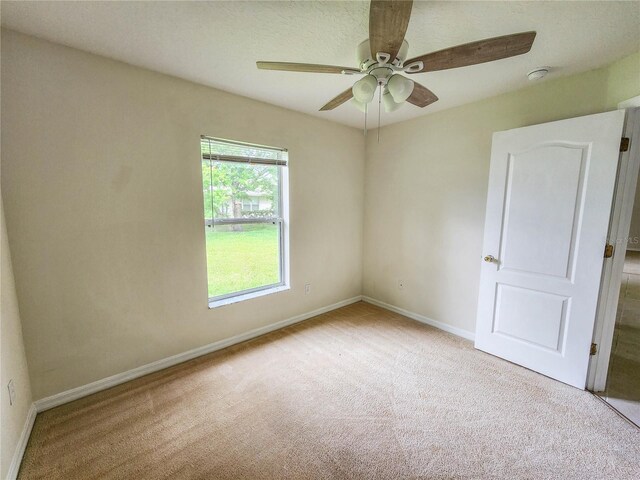 spare room with ceiling fan and light colored carpet