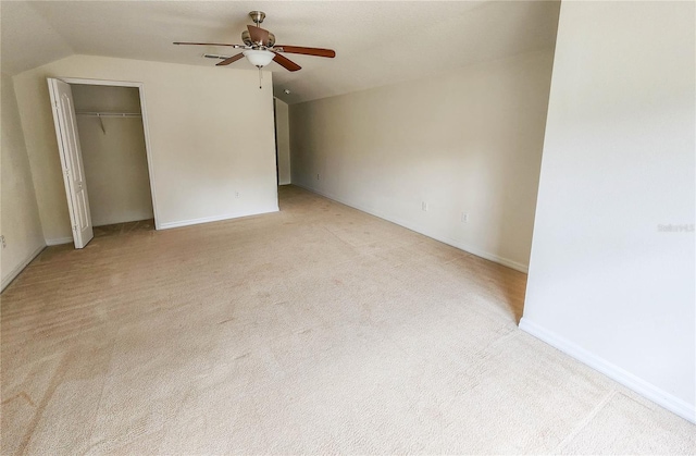 unfurnished bedroom with ceiling fan, a closet, light colored carpet, and vaulted ceiling