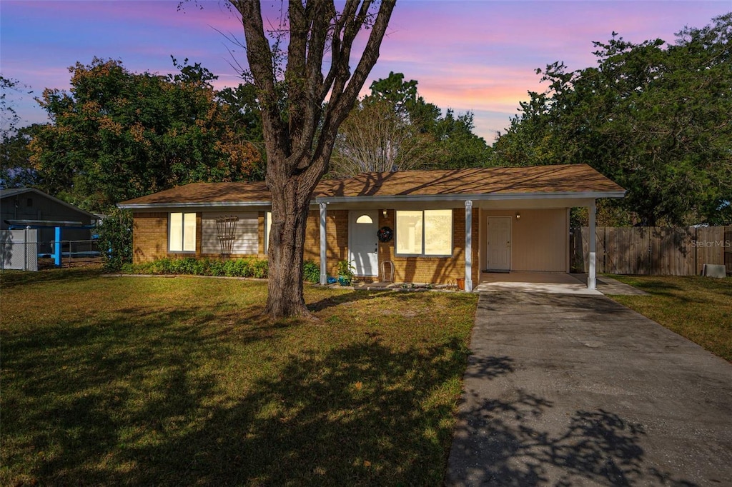 ranch-style house featuring a carport and a lawn