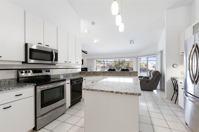 kitchen with a center island, hanging light fixtures, decorative backsplash, appliances with stainless steel finishes, and white cabinetry