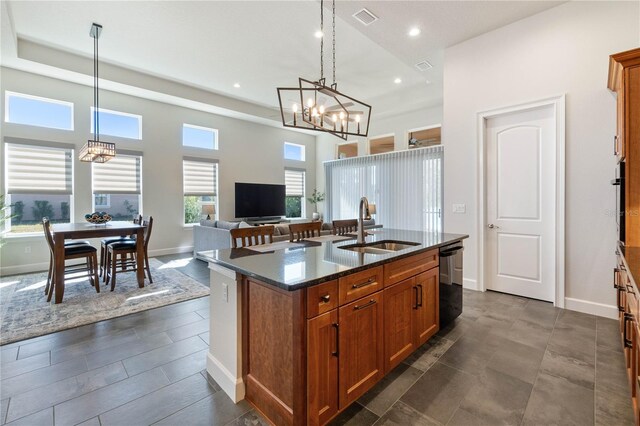 kitchen with hanging light fixtures, a kitchen island with sink, dishwasher, and sink