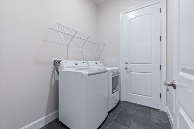 clothes washing area with dark tile patterned flooring and washer and clothes dryer