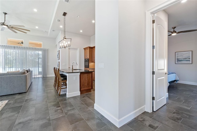 kitchen featuring sink, pendant lighting, black oven, a kitchen island with sink, and a breakfast bar