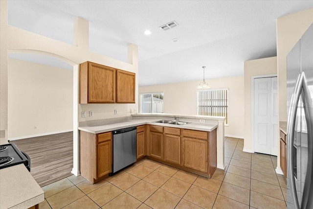 kitchen featuring pendant lighting, sink, light tile patterned floors, stainless steel appliances, and kitchen peninsula