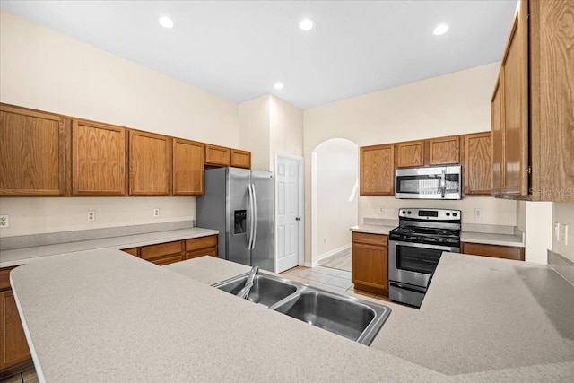 kitchen featuring sink, stainless steel appliances, kitchen peninsula, and light tile patterned flooring